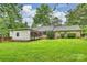 Brick home with well-manicured backyard featuring a lawn, trees, and a detached white garage, with an adjacent brick privacy wall at 1961 Runnymede Ln, Charlotte, NC 28211