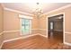 Well-lit dining room with a chandelier, wainscoting, and hardwood floors, offering a view into the living area at 1961 Runnymede Ln, Charlotte, NC 28211