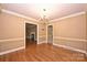 Spacious dining room featuring wainscoting, a chandelier, and hardwood floors, connecting to other living spaces at 1961 Runnymede Ln, Charlotte, NC 28211