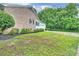 Brick home exterior showing lush green lawn, manicured shrubbery and a paved driveway leading to an attached garage at 1961 Runnymede Ln, Charlotte, NC 28211