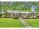 Charming brick home featuring a beautifully landscaped front yard with lush green grass and mature trees at 1961 Runnymede Ln, Charlotte, NC 28211
