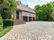 Charming stone home with brick driveway and three-car garage, surrounded by lush landscaping at 2240 La Maison Dr, Charlotte, NC 28226
