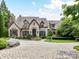 Stunning stone house with a circular driveway and manicured landscaping for enhanced curb appeal at 2240 La Maison Dr, Charlotte, NC 28226
