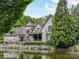 Stunning stone home with a lakefront view, beautiful landscaping, and turret architectural detail at 2240 La Maison Dr, Charlotte, NC 28226