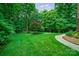 Beautiful backyard with lush green lawn, a curved walkway, and mature trees providing shade and privacy at 2314 Winding Oaks Trl, Waxhaw, NC 28173
