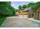 View of a stately brick home showcasing a three-car garage and lush greenery surrounding the property at 2314 Winding Oaks Trl, Waxhaw, NC 28173