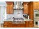 Close up of a kitchen featuring stainless steel stove with hood, custom cabinets, and tile backsplash at 2314 Winding Oaks Trl, Waxhaw, NC 28173