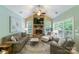 Comfortable living room featuring stone fireplace, a ceiling fan, and large windows providing ample light at 2314 Winding Oaks Trl, Waxhaw, NC 28173