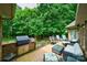 Outdoor patio with a built-in grill, ample seating, and a serene backdrop of mature trees at 2314 Winding Oaks Trl, Waxhaw, NC 28173