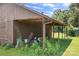 Covered area on side of the barn with overgrown vegetation and some stored items at 24008 Carriker Rd, Albemarle, NC 28001