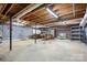 Unfinished basement with exposed wood ceiling, concrete flooring, and brick fireplace at 24008 Carriker Rd, Albemarle, NC 28001