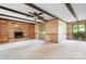 Spacious living room featuring a stone fireplace, built-in shelving, beamed ceilings, and natural light at 24008 Carriker Rd, Albemarle, NC 28001