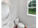 Bright half bathroom featuring a round mirror and window with neighborhood views at 2479 N Legacy Park Blvd, Fort Mill, SC 29707