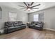Spacious living room featuring hardwood floors, a modern ceiling fan, and two reclining leather couches at 301 Honeywood Ave, Charlotte, NC 28216