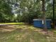 A shed with blue siding sits on a large lot, surrounded by trees, in this backyard view at 5458 Foxcroft Dr, Fort Lawn, SC 29714