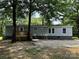 Charming one-story home with light green siding, stone facade, and a wooden porch framed by mature trees at 5458 Foxcroft Dr, Fort Lawn, SC 29714