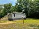 Charming one-story home with light green siding, a wooden porch, and surrounded by large trees at 5458 Foxcroft Dr, Fort Lawn, SC 29714