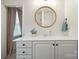 Bright bathroom features white cabinets, modern fixtures, round wood-trimmed mirror, and quartz countertop at 7931 Baylis Dr, Huntersville, NC 28078
