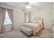 Cozy bedroom with large windows, soft pink accents, and a comfortable upholstered bed with bench at 7931 Baylis Dr, Huntersville, NC 28078