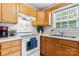 A kitchen view displaying a double sink, a white stove, wood cabinets and lots of natural light at 1028 Pocono Pl, Newton, NC 28658