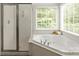 Serene bathroom featuring a soaking tub with shower, bright window, and tiled surround, creating a relaxing oasis at 11139 Tradition View Dr, Charlotte, NC 28269