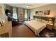 Spacious bedroom with dark wood floors, neutral walls, three windows, ceiling fan, and decorative art at 114 Mint Ave # A, Mooresville, NC 28117