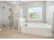 Bright bathroom featuring a soaking tub, a glass shower, and tile surround at 16229 Loch Raven Rd, Huntersville, NC 28078