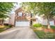 Charming two-story brick home featuring a white garage door, landscaped yard, and mature trees at 16525 Kettlewell Ln, Charlotte, NC 28277