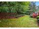 Landscaped backyard featuring vibrant greenery, mulch beds, and a charming red deck with steps at 1720 Mountain Park Dr, Charlotte, NC 28214
