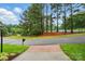 View of the exterior with a manicured lawn, mature trees, and community tennis court in the background at 1720 Mountain Park Dr, Charlotte, NC 28214
