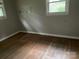 Shows a bedroom with damaged hardwood floors, gray walls, and two windows at 1769 S Nc 16 Hwy, Denver, NC 28037