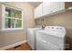 Modern laundry room with full-size washer and dryer, storage cabinets and a bright window at 21621 Crown Lake Dr, Cornelius, NC 28031
