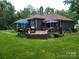 A spacious wooden back deck is furnished with outdoor seating and umbrellas overlooking the landscaped backyard at 2777 Old South Nw Ct, Concord, NC 28027