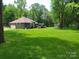 Expansive backyard with mature trees and manicured lawn, featuring a deck and detached shed at 2777 Old South Nw Ct, Concord, NC 28027
