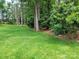 A view of the home's large landscaped backyard with trimmed grass and mature trees at 2777 Old South Nw Ct, Concord, NC 28027