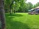 A view of the home's spacious backyard with trimmed grass, mature trees and a wooden back deck at 2777 Old South Nw Ct, Concord, NC 28027