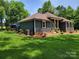 Side view of well-maintained home with landscaped yard, featuring a deck and manicured lawn at 2777 Old South Nw Ct, Concord, NC 28027