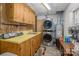 A functional laundry room with a stacked washer/dryer, utility sink, and ample storage space with wooden cabinets at 310 Yarbro Rd, Kings Mountain, NC 28086
