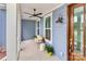 Close up of the cozy front porch with a ceiling fan, wood door, seating with pillows, and plants at 332 Canvasback Rd, Mooresville, NC 28117