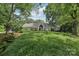 Green single-story home with red shutters surrounded by lush trees and a sloping lawn at 3916 Blowing Rock Way, Charlotte, NC 28210
