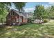 A beautiful brick home featuring a well-manicured lawn, mature trees, and an inviting backyard patio at 3916 Blowing Rock Way, Charlotte, NC 28210