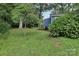 Lush backyard featuring mature trees and landscaping surrounding a charming blue cottage-style home at 407 Cherry St, Belmont, NC 28012