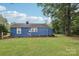 Quaint blue home featuring white trim, a brick chimney, and a spacious backyard with mature trees at 407 Cherry St, Belmont, NC 28012