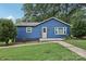 Charming blue single-story home with a yellow door, set against a backdrop of mature trees at 407 Cherry St, Belmont, NC 28012