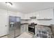 Galley kitchen featuring stainless steel appliances, white cabinets, and stone-look countertops at 407 Cherry St, Belmont, NC 28012