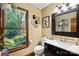Bathroom featuring dark vanity, a black-framed mirror, and a view of the greenery outside at 4848 Spicewood Dr, Charlotte, NC 28227