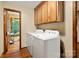 A bright laundry room features white appliances and wood cabinets with a view into the backyard at 4848 Spicewood Dr, Charlotte, NC 28227