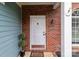 Close-up of a white front door with brick trim, a welcome mat, and decorative plants at 8906 Pickering Grove Ln, Charlotte, NC 28216