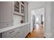 Butler's pantry with gray cabinets, brass hardware, white countertop, and hardwood floors at 104 Edgewater Park St, Davidson, NC 28036