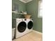 This laundry room features modern, white, side-by-side washer and dryer units with shelving at 10672 Barberville Rd, Fort Mill, SC 29707